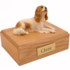 Laying brown and white King Charles Spaniel dog figurine on wood memorial cremation urn