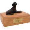 Laying black labrador retriever dog figurine on wood memorial cremation urn