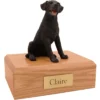 Sitting black labrador retriever dog figurine on wood memorial cremation urn