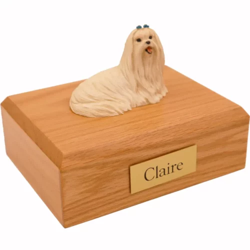 Laying maltese dog figurine on wood memorial cremation urn