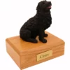 Sitting black newfoundland dog figurine on wood memorial cremation urn