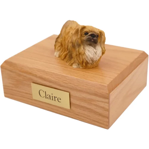 Laying tan Pekingese dog figurine on wood memorial cremation urn