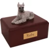 Laying silver schnauzer dog figurine on wood memorial cremation urn