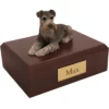 Laying black and silver ears down schnauzer dog figurine on wood memorial cremation urn