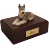 Laying tari ears down schnauzer dog figurine on wood memorial cremation urn