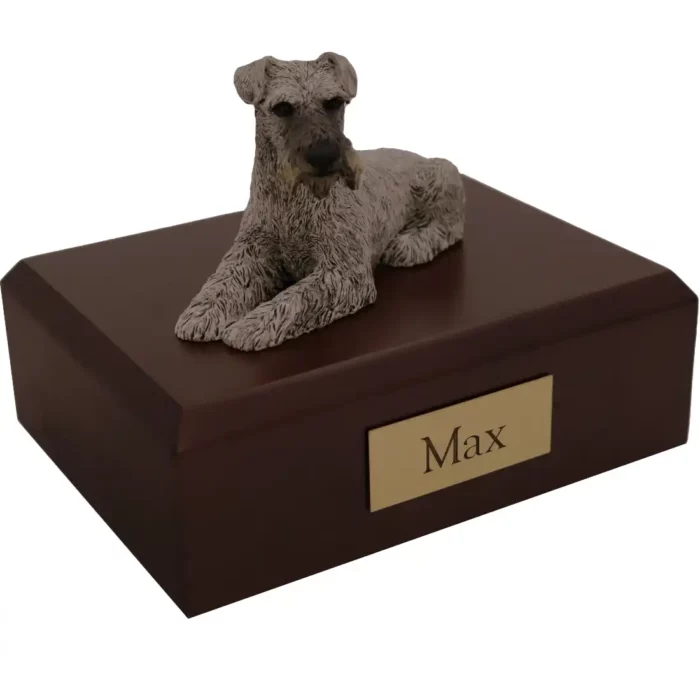 Laying silver ears down schnauzer dog figurine on wood memorial cremation urn