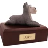 Laying gray ears up schnauzer dog figurine on wood memorial pet cremation urn