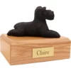 Laying black ears down schnauzer dog figurine on wood memorial pet cremation urn