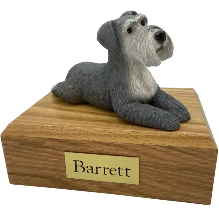Laying gray ears down schnauzer dog figurine on wood memorial pet cremation urn
