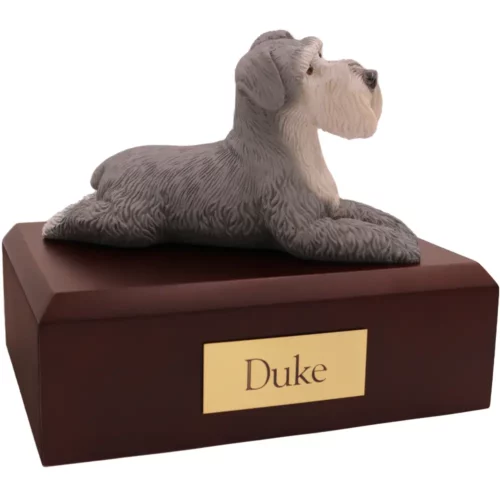 Laying gray ears down schnauzer dog figurine on wood memorial pet cremation urn