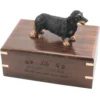Black and tan longhaired dachshund dog figurine on wood cremation urn, engraved wood
