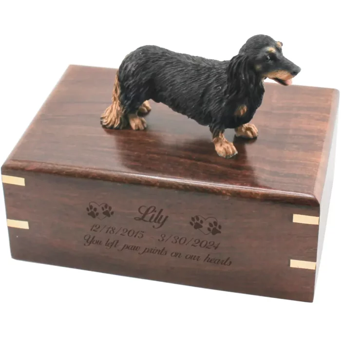 Black and tan longhaired dachshund dog figurine on wood cremation urn, engraved wood