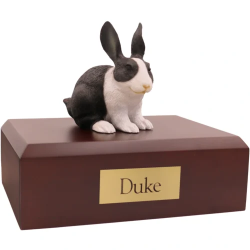 Black and white rabbit figurine on wood cremation urn
