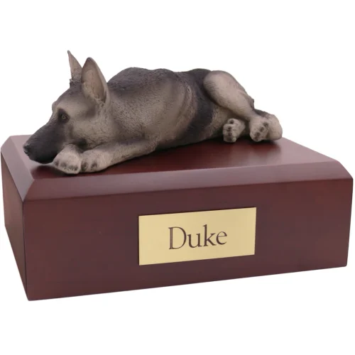 Laying black and silver German Shepherd dog figurine on wood cremation urn