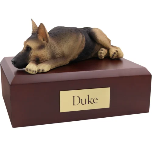 Laying black and tan German Shepherd dog figurine on wood cremation urn