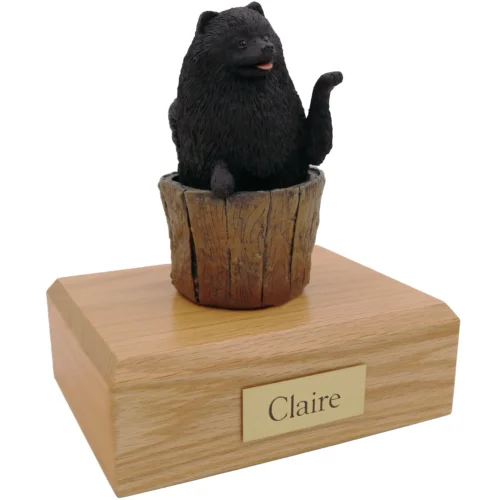 Black Pomeranian dog figurine on wood cremation urn