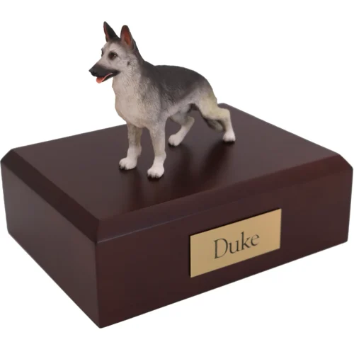 Standing silver and black German Shepherd dog figurine on wood cremation urn