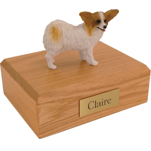 Brown and white papillon dog figurine on wood cremation urn