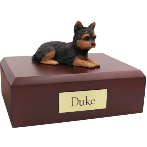 Laying yorkie yorkshire terrier dog figurine on wood cremation urn